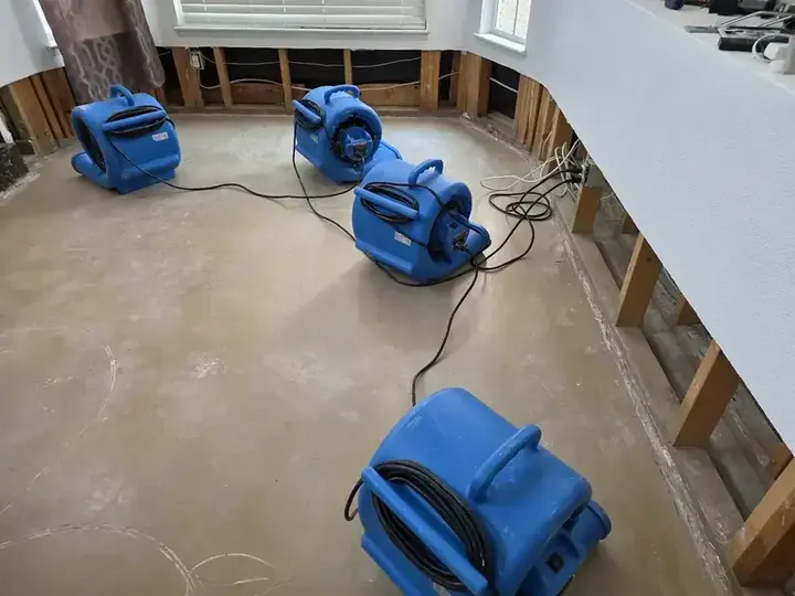Air movers drying a bare slab after water damage in Beaverton